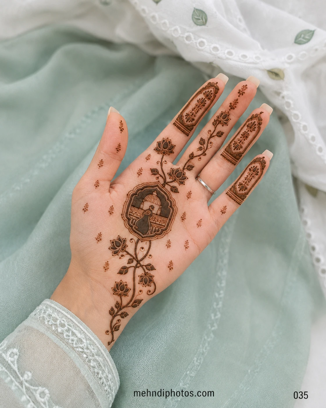 Front hand mehndi design featuring a peacock inside an ornamental arch, surrounded by lotus vines and detailed finger panels