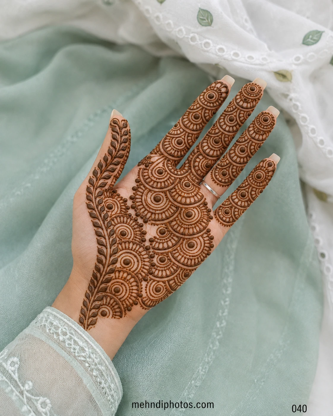 Full front hand mehndi design featuring layered semicircular patterns across the palm and fingers with a long leafy border