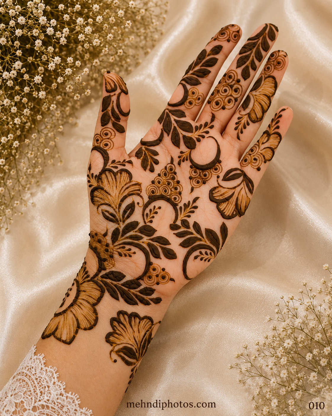 Front hand mehndi design featuring large shaded flowers, bold leafy vines, curved motifs and circular decorative details across the palm and fingers.
