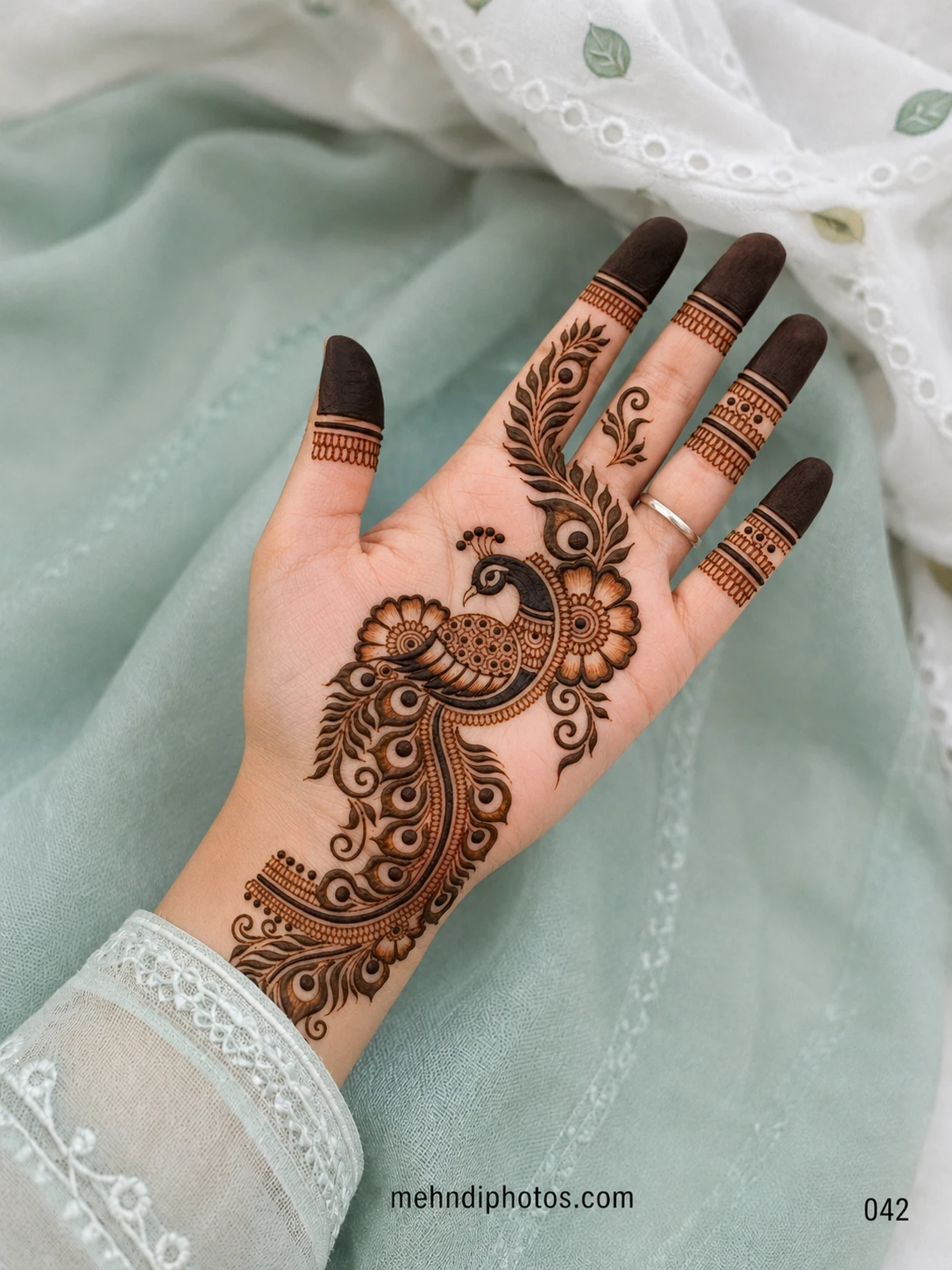Explore a royal front hand mehndi design with an intricate peacock, floral details and feather motifs, perfect for weddings and festive occasions.