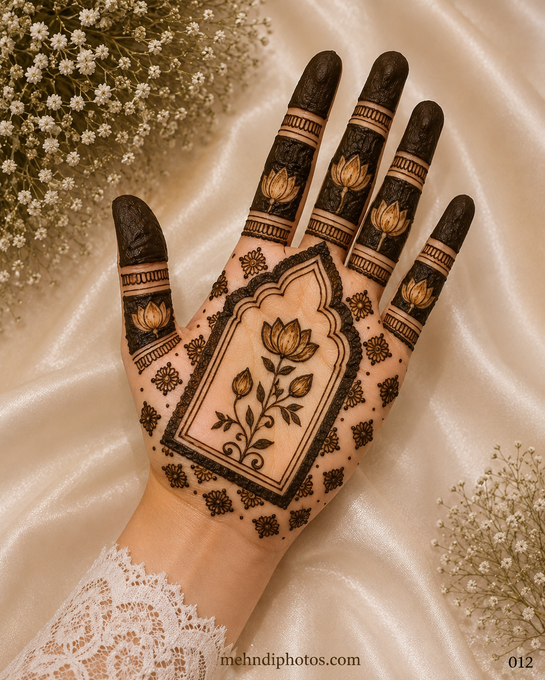 Front hand mehndi design with a central lotus inside a temple-style arch, small floral motifs, dark finger bands and shaded fingertips.