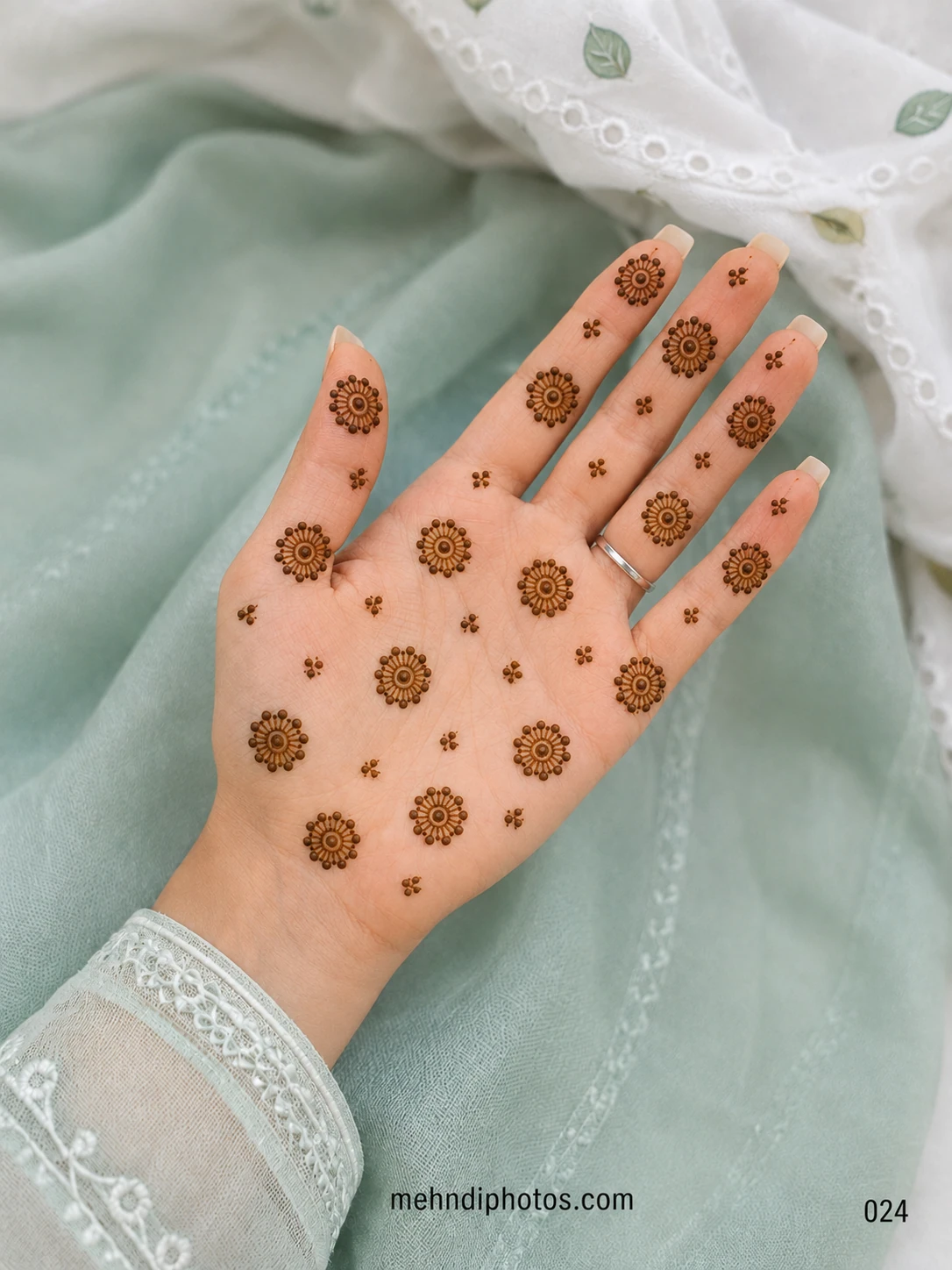 Simple front hand mehndi design with evenly spaced circular sunflower motifs and tiny floral accents across the palm and fingers