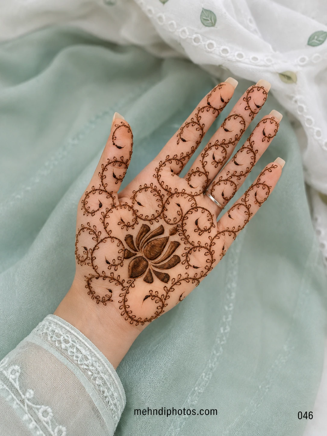 Front hand mehndi design featuring a shaded lotus on the palm surrounded by delicate spiral vines extending across every finger