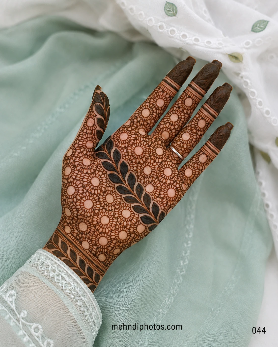 Full front hand mehndi design featuring a dense floral lace pattern, bold diagonal leafy branch, wrist border and dark fingertips