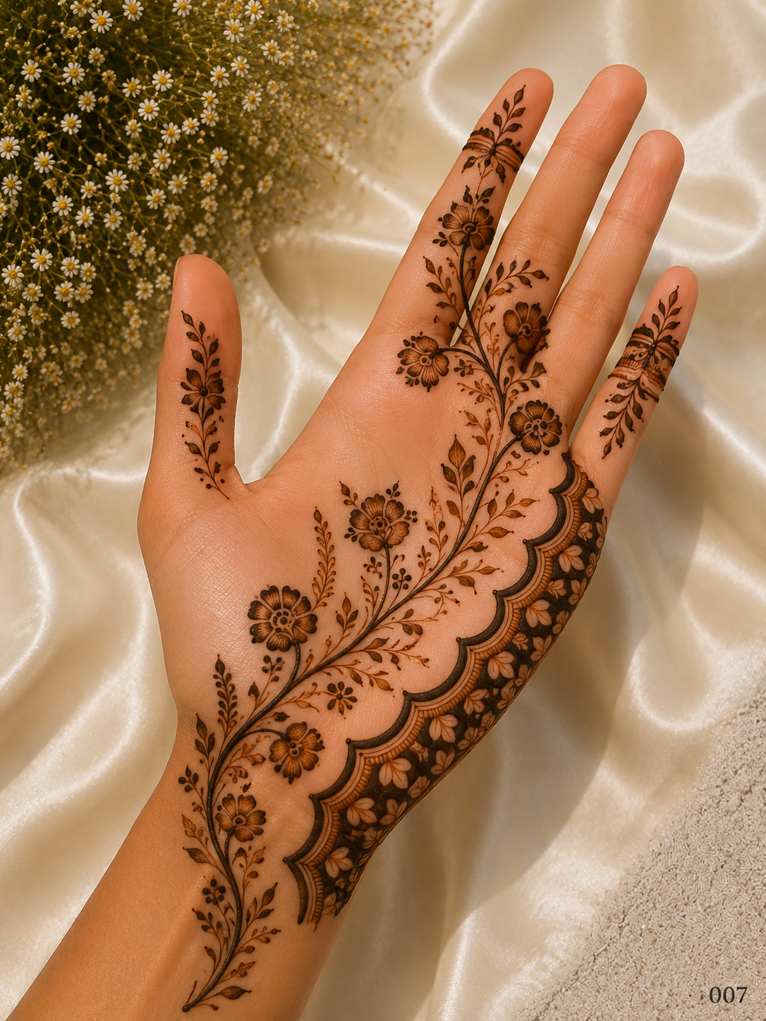 Simple front hand mehndi design with a diagonal floral vine, shaded flowers, leafy branches and a scalloped floral border along one side.