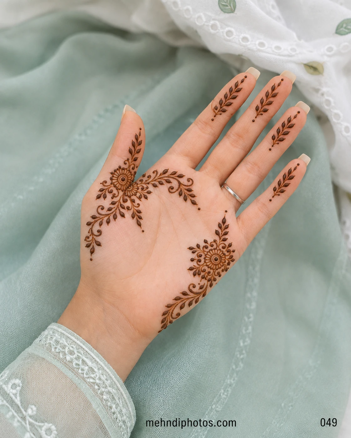 Minimal front hand mehndi design with two side floral motifs, curling leafy vines and matching leaf sprigs on each finger