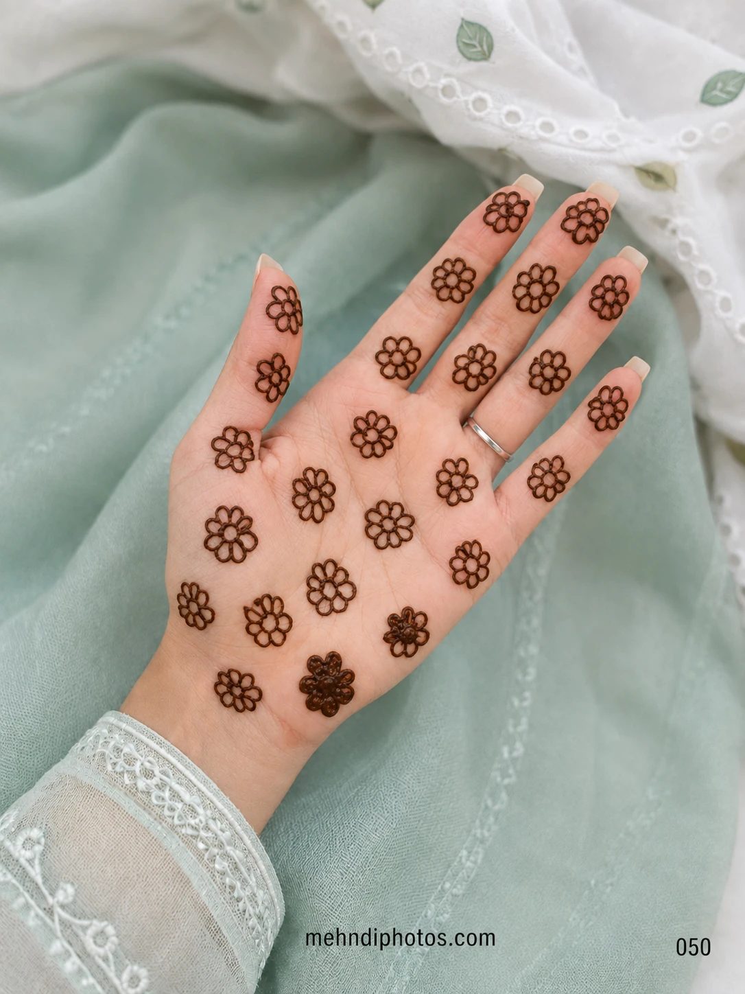 Simple front hand mehndi design featuring small outline flowers scattered evenly across the palm and fingers
