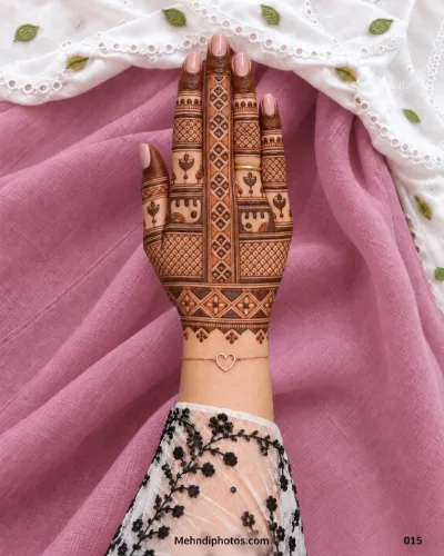 Diwali back hand mehndi design with a vertical geometric panel, small diya motifs, lattice patterns, dark fingertips, finger bands, and a decorative wrist border.