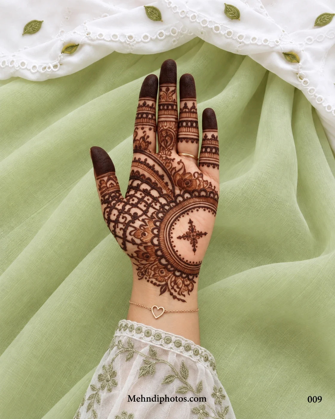 Front hand with a circular mandala mehndi design, floral-star centre, latticework, scalloped borders, finger bands and dark fingertips.