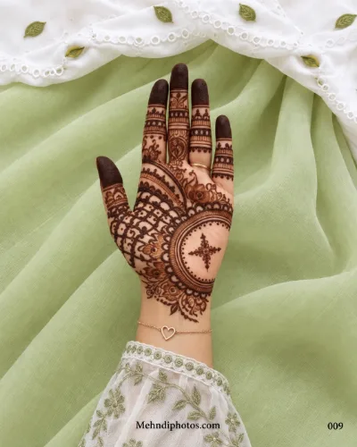 Front hand with a circular mandala mehndi design, floral-star centre, latticework, scalloped borders, finger bands and dark fingertips.