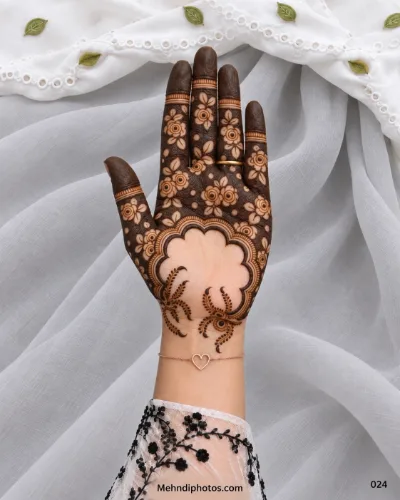 Eid front hand mehndi with negative-space flowers, dark fingertips, an open scalloped palm frame, and dotted sprays near the wrist.