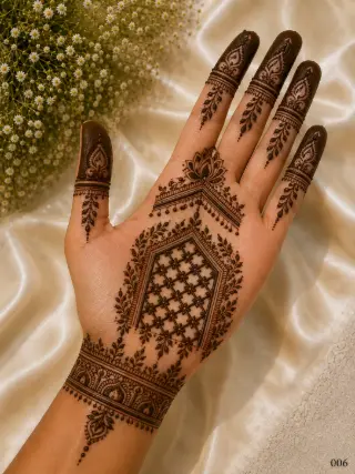 Simple front hand mehndi design featuring a lotus motif, geometric floral jaali panel, leafy borders, ornate wrist band and dark fingertips.