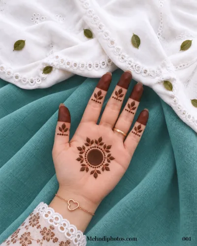 Discover Mehndi Design 001, featuring a bold gol tikki, leafy sunburst motifs, dotted accents, and shaded fingertips for an elegant festive look.