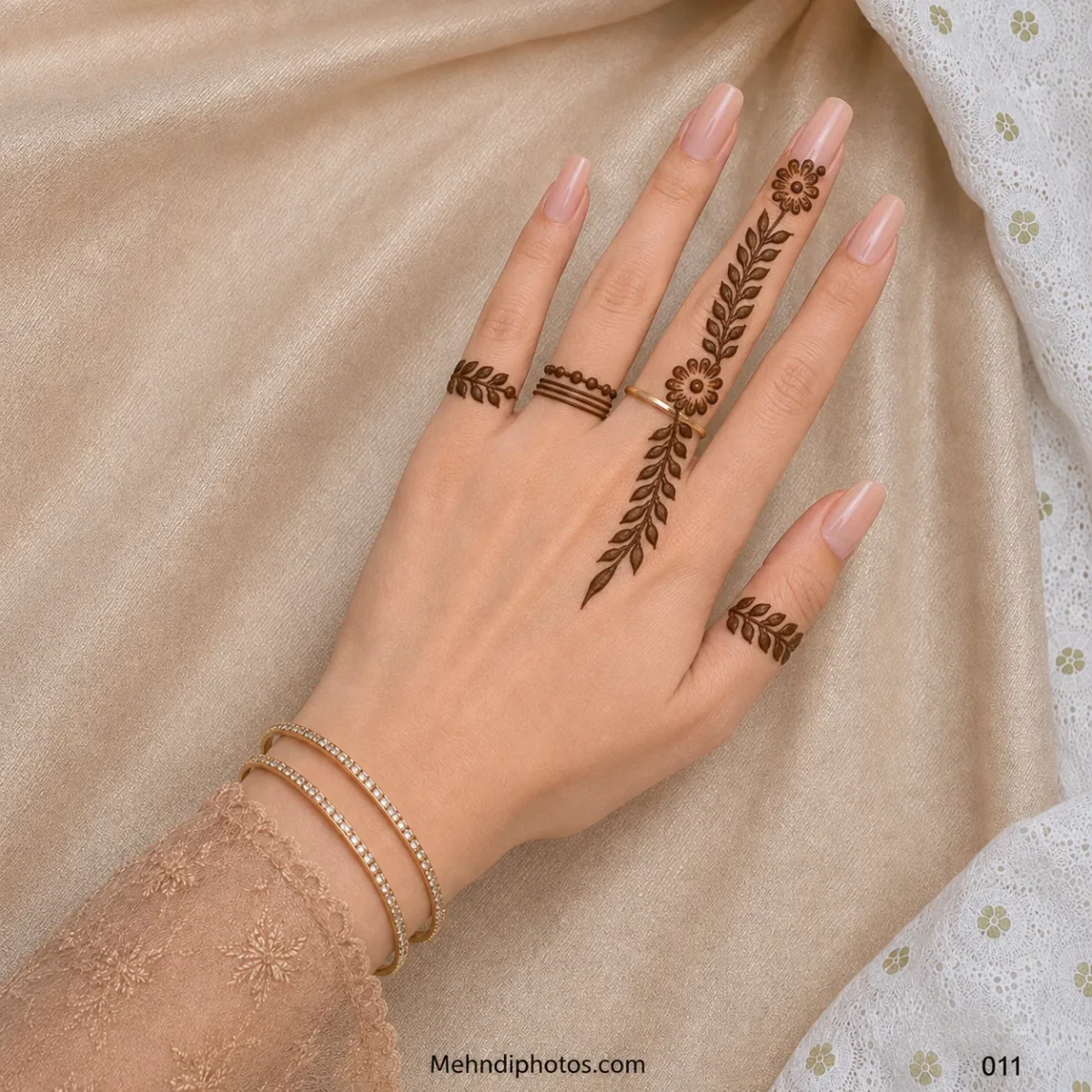 Back hand with a floral leafy vine extending from the ring finger, small leaf bands and minimal ring-style mehndi details.