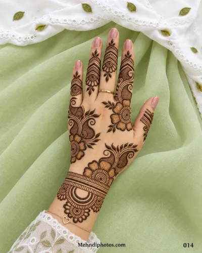 Back hand mehndi design with large shaded flowers, paisley patterns, leafy branches, mesh detailing, finger bands, and a floral wrist motif.