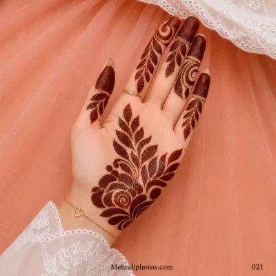 Front hand with a bold rose mehndi motif, sweeping leafy branches, curved vines and dark filled fingertips.