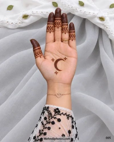 Minimal Eid front hand mehndi featuring a crescent moon and stars on the palm with dark fingertips and leafy finger bands.