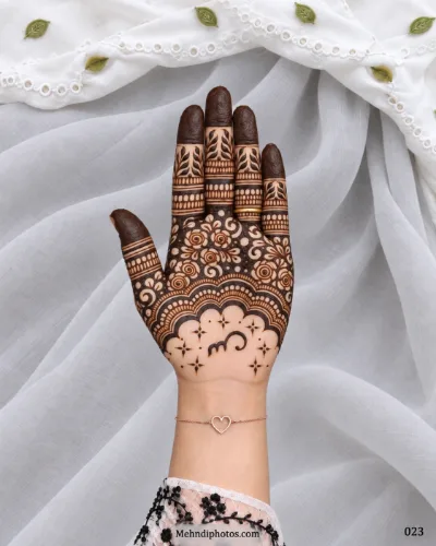 Eid front hand mehndi featuring dense spiral flowers above a layered scalloped arch with starbursts, a central flourish, and dark fingertips.
