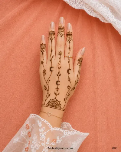 Back hand with crescent moon motifs, delicate leafy vines, ornamental finger bands and a semicircular mehndi design near the wrist.