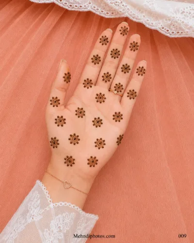 Front hand decorated with evenly spaced spiral gol tikki mehndi motifs surrounded by small raised dots.