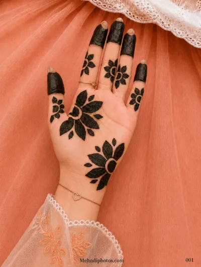 Front hand with dark filled fingertips, bold flower motifs and large leafy mehndi patterns across the palm and wrist.