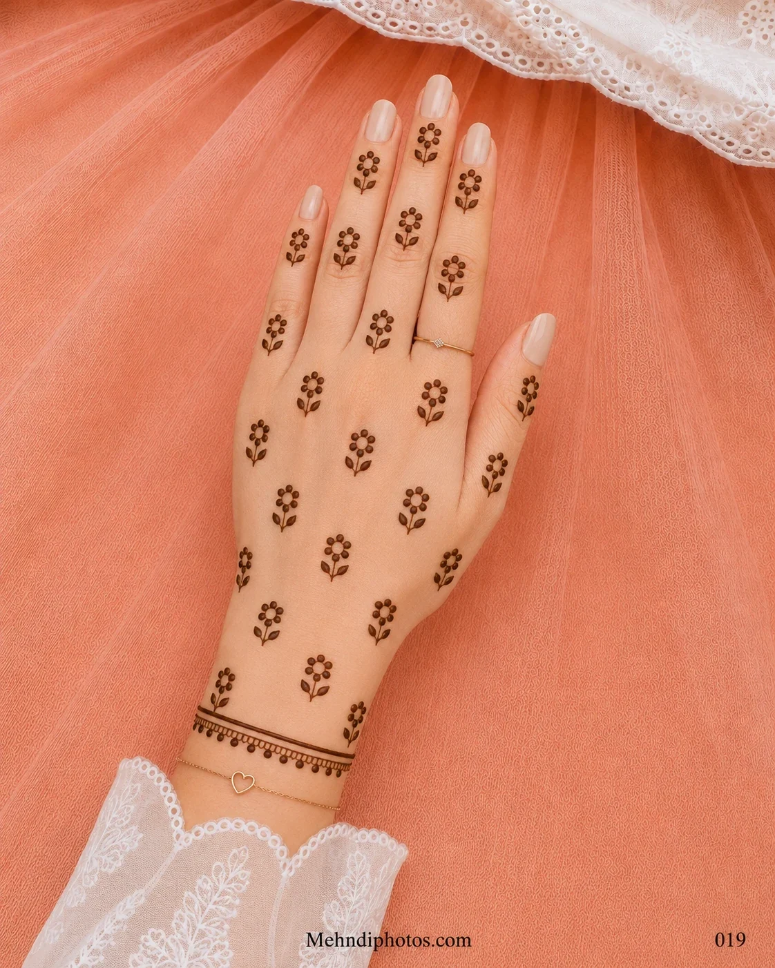 Back hand decorated with evenly scattered tiny flower sprigs and a fine bracelet-style mehndi border with hanging dots at the wrist.
