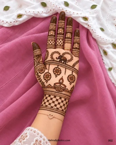 Diwali front hand mehndi design featuring a decorated elephant, diya, hanging floral motifs, leafy vines, lotus fingers, and netted wrist details.