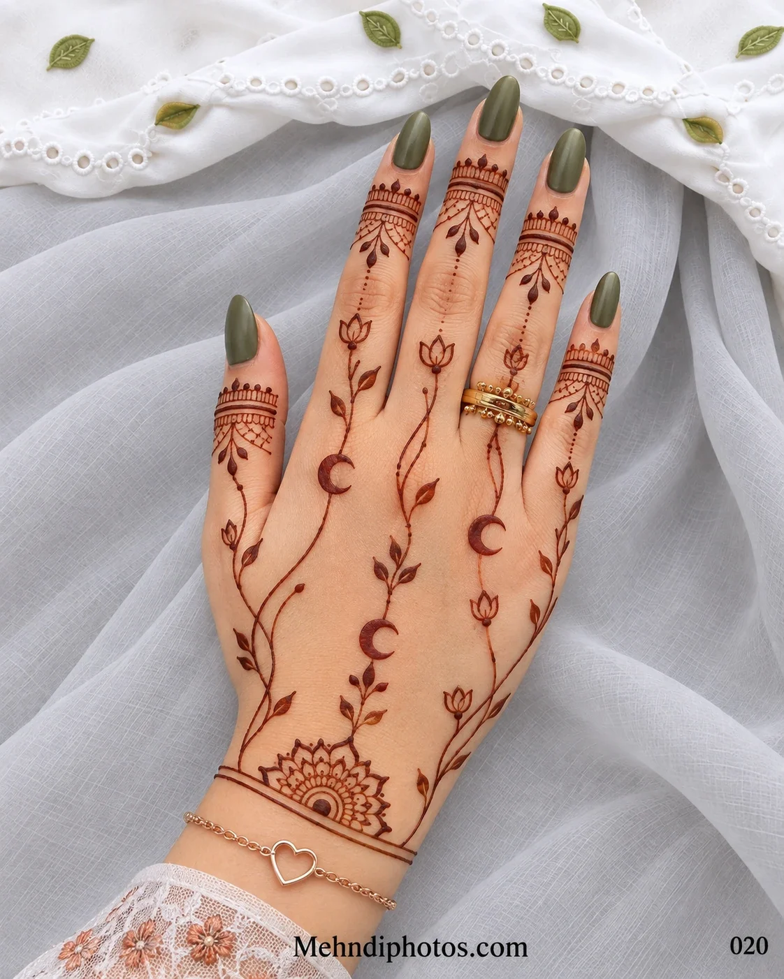 Eid back hand mehndi featuring slender lotus vines, crescent moons, leafy finger bands, a wrist half-mandala, and olive-green nails.