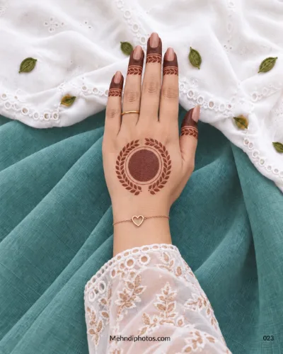 Back-hand mehndi with solid gol tikki, laurel leaf wreath, and matching fingertip bands