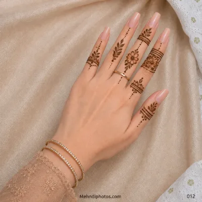 Back hand with simple floral finger mehndi, leafy sprigs, decorative bands and delicate vertical dotted trails.
