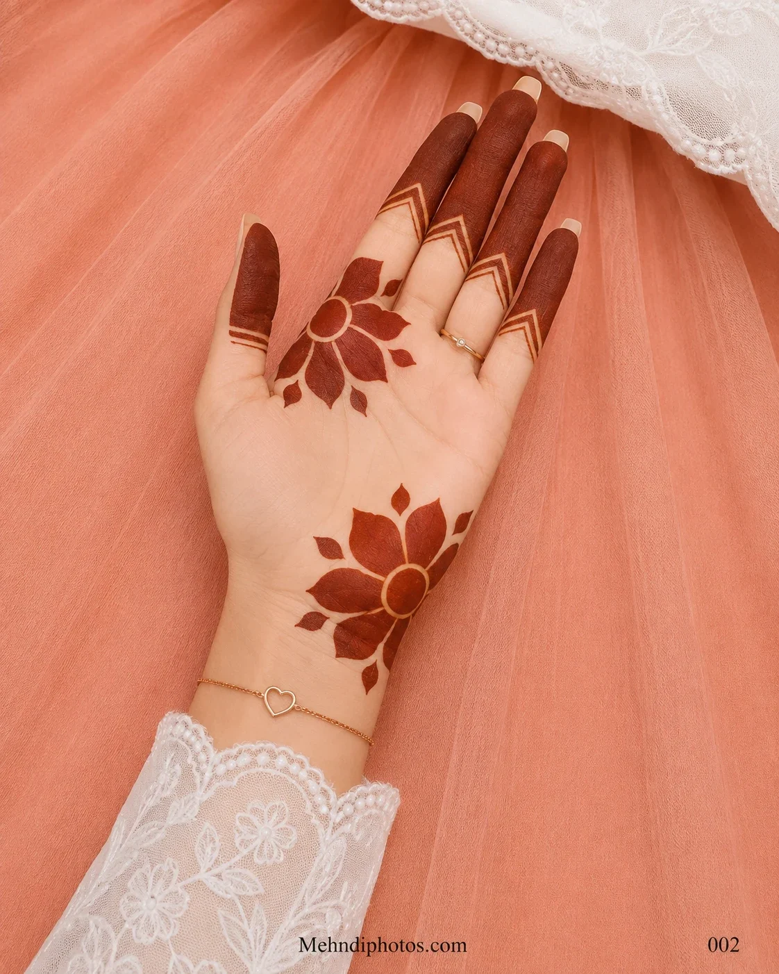 Front hand with two bold lotus mehndi motifs, dark filled fingers and clean chevron borders above the finger joints.