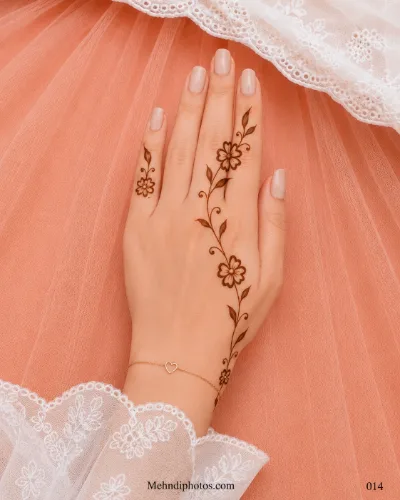 Back hand with a slim floral mehndi vine extending from the wrist to the ring finger, featuring shaded leaves and curled stems.