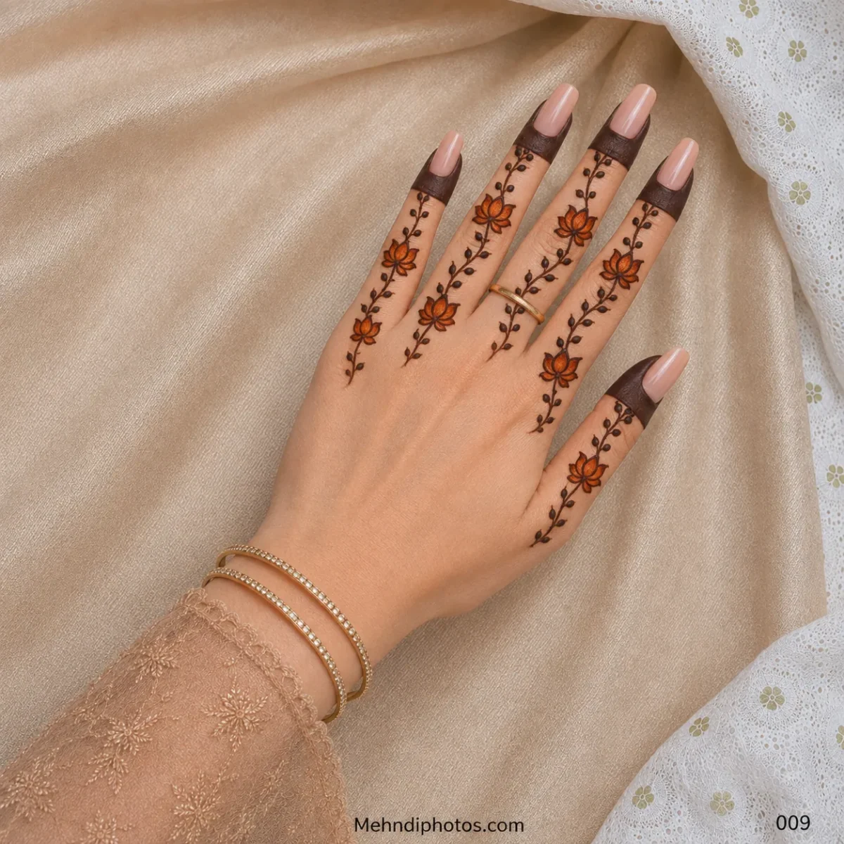 Back hand with orange lotus flowers and delicate leafy mehndi vines extending along each finger beneath dark fingertip bands.