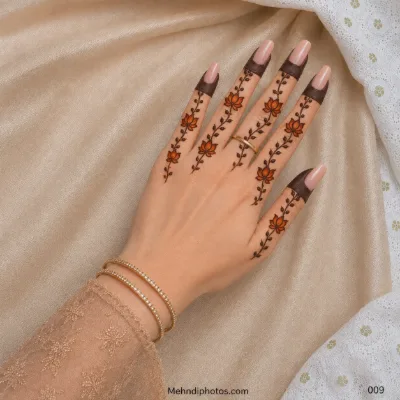 Back hand with orange lotus flowers and delicate leafy mehndi vines extending along each finger beneath dark fingertip bands.