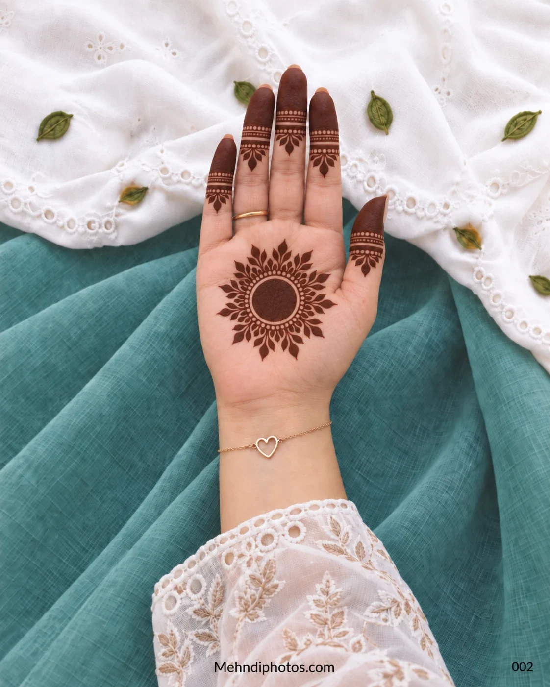 Front hand with floral sunburst gol tikki and banded fingertip mehndi