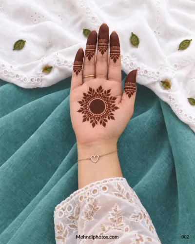 Front hand with floral sunburst gol tikki and banded fingertip mehndi