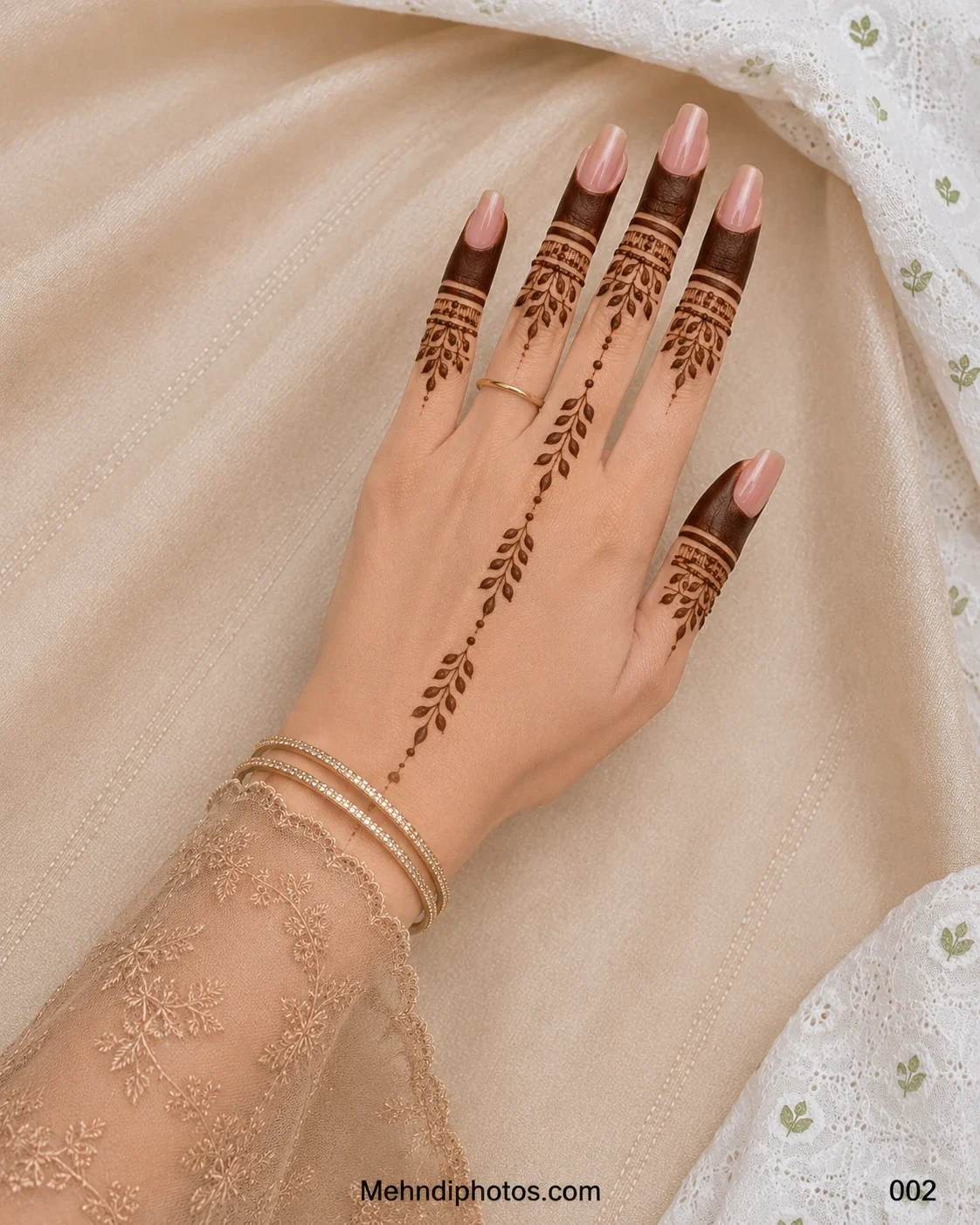 Back hand with filled fingertip mehndi, decorative finger bands and a delicate dotted leafy vine extending toward the wrist.
