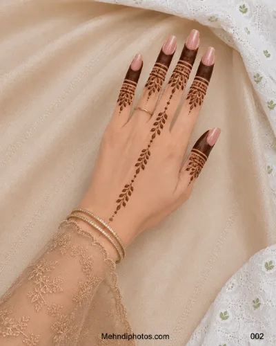 Back hand with filled fingertip mehndi, decorative finger bands and a delicate dotted leafy vine extending toward the wrist.