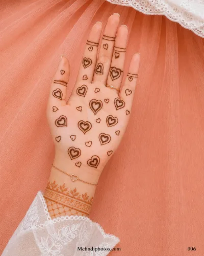 Front hand with scattered double-outline heart mehndi motifs, simple finger bands and a delicate leafy bracelet design near the wrist.