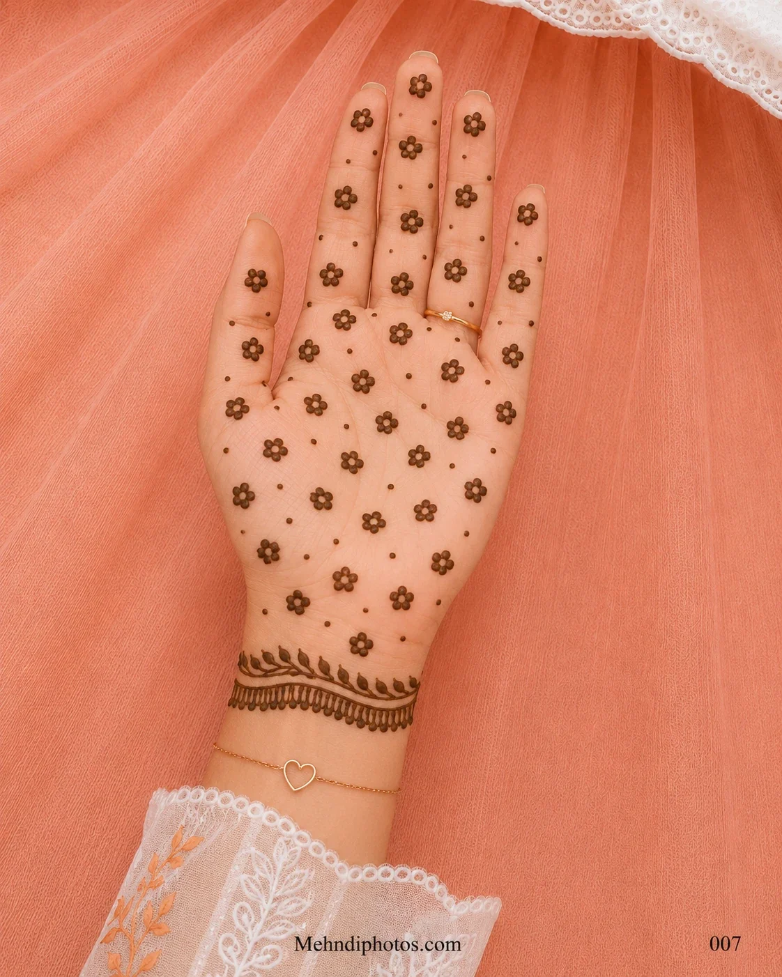 Front hand covered with tiny five-petal mehndi flowers and dots, finished with a leafy bracelet-style border at the wrist.