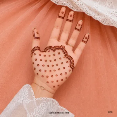Front hand with tiny dotted flowers across the lower palm, a bold scalloped border and geometric framed fingertip mehndi panels.