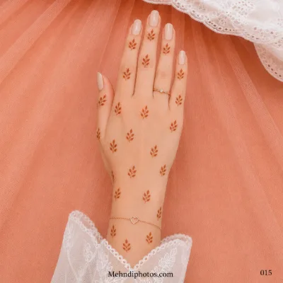 Back hand decorated with evenly scattered tiny leafy mehndi sprigs across the fingers, hand and wrist.