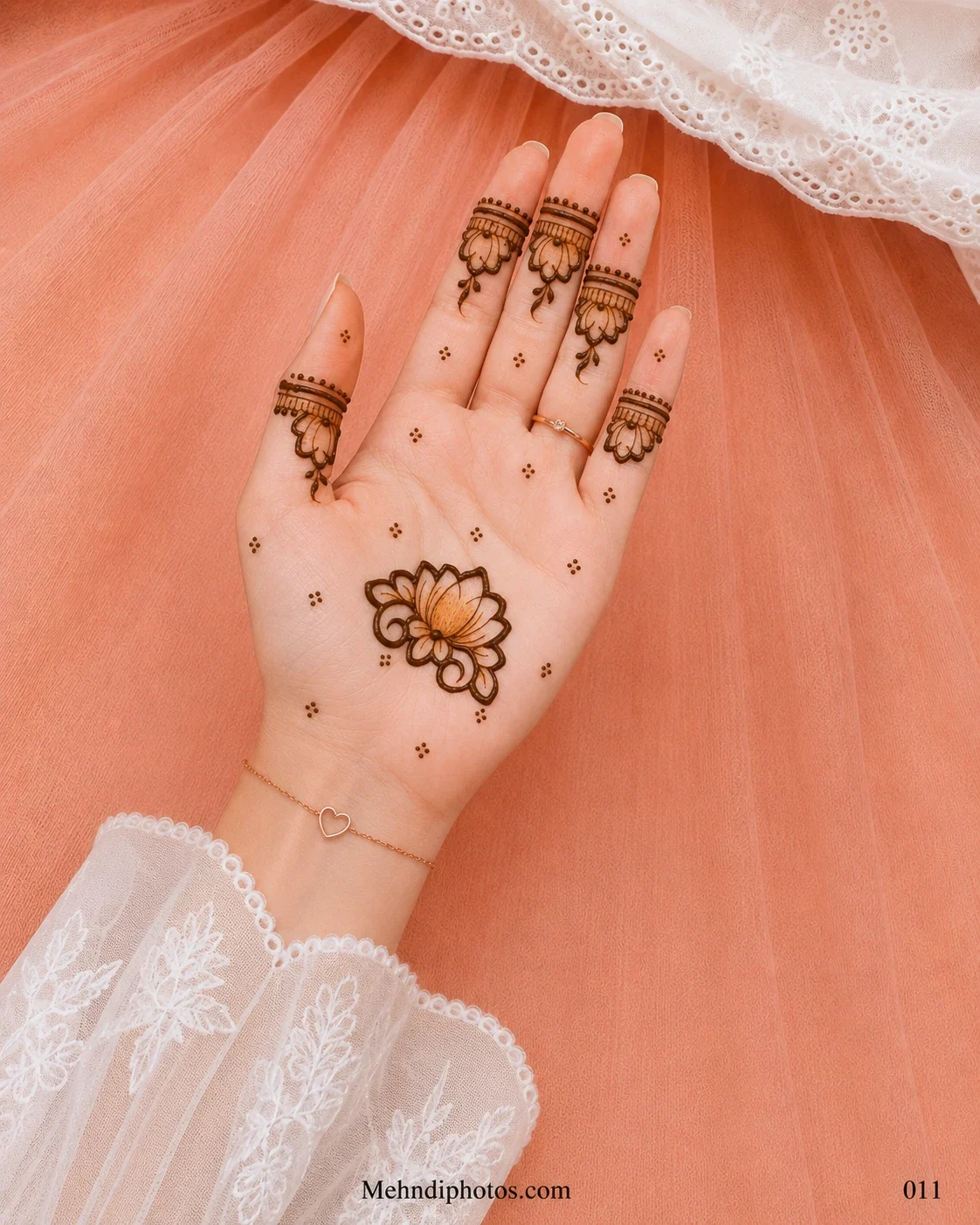Front hand with a central lotus mehndi motif, hanging floral finger bands and small dot clusters across the open palm.