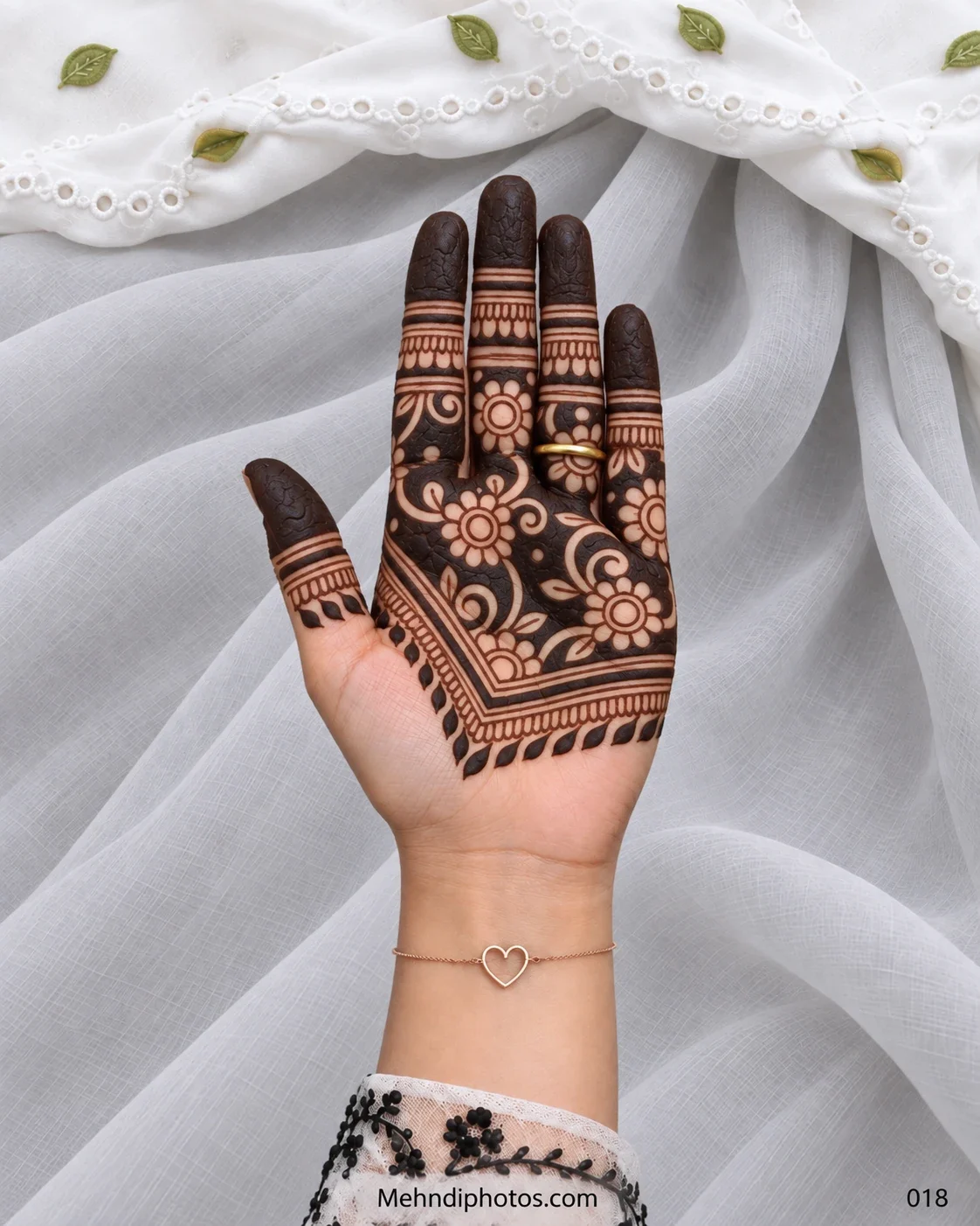 Eid front hand mehndi featuring bold negative-space flowers and vines across the upper palm with dark fingertips and a V-shaped leafy border.