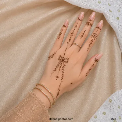 Back hand with a delicate bow motif, hanging leafy mehndi vines, dotted trails, tiny stars and minimal finger details.