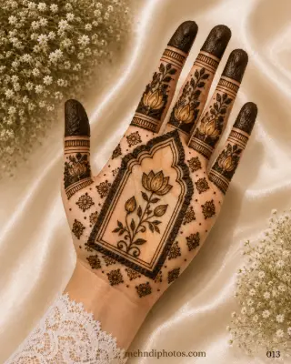 Front hand mehndi design with a lotus flower inside a temple-style arch, small floral motifs, leafy finger patterns and dark shaded fingertips.