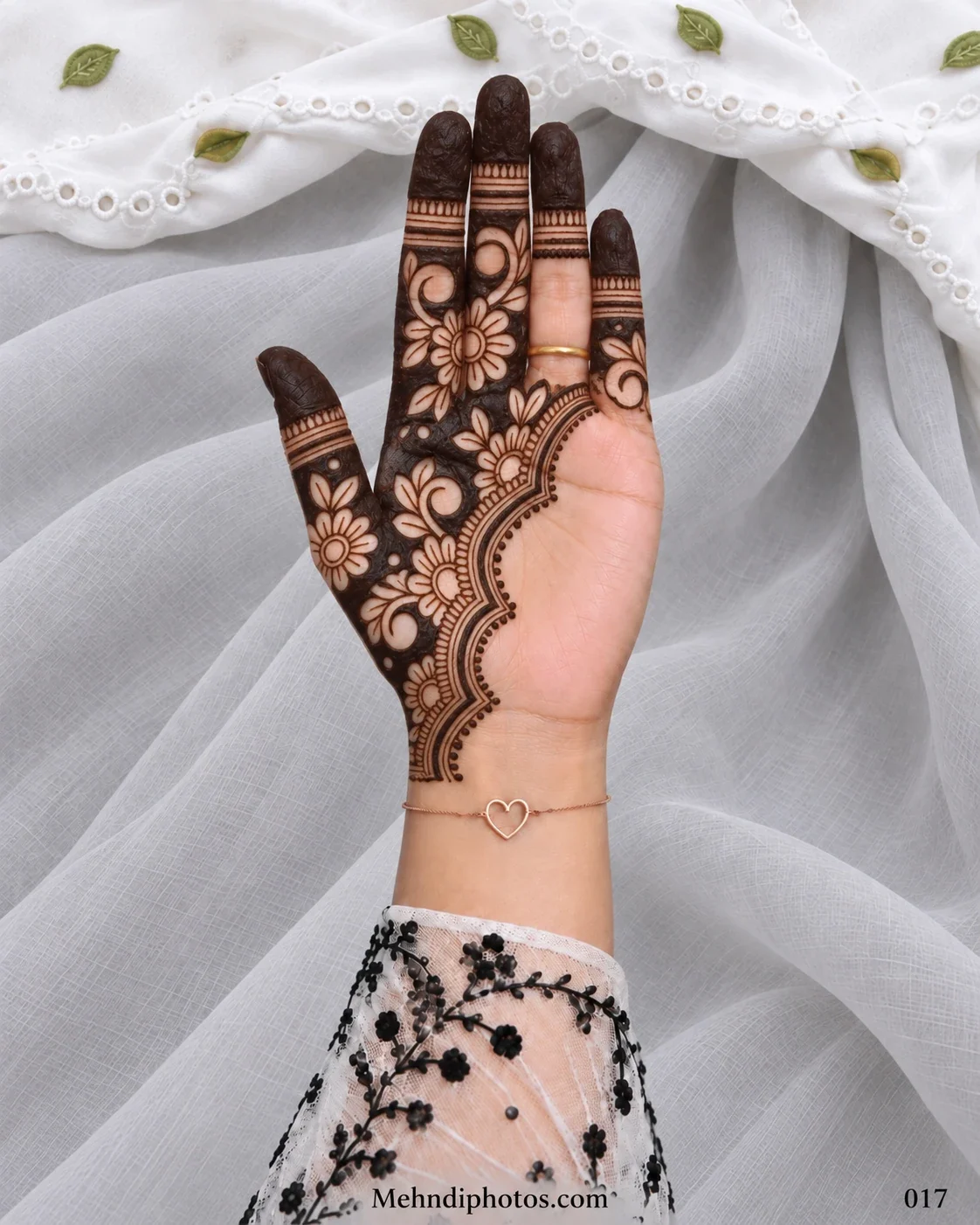 Arabic-style Eid front hand mehndi featuring dense flowers and curved vines on one side with dark fingertips and a layered scalloped border.