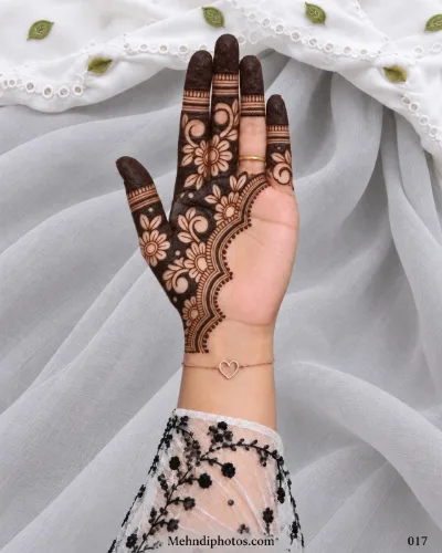 Arabic-style Eid front hand mehndi featuring dense flowers and curved vines on one side with dark fingertips and a layered scalloped border.