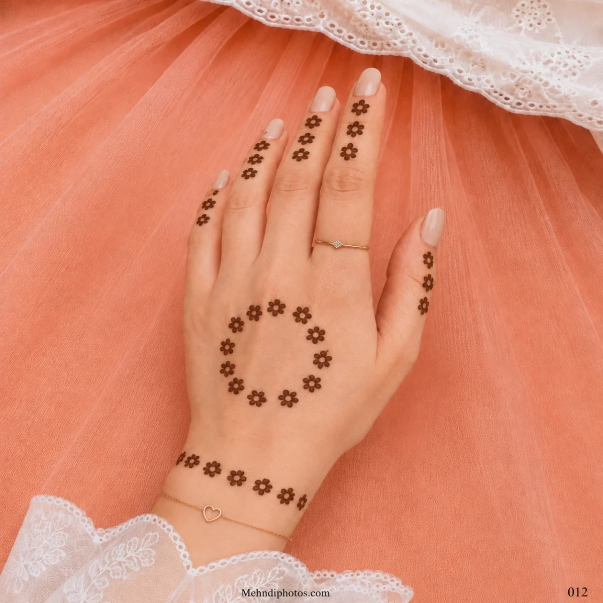 Back hand with a circle of small floral mehndi motifs, matching flower trails on the fingers and a floral bracelet near the wrist.