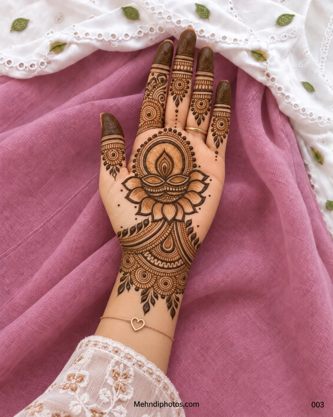 Diwali front hand mehndi design featuring a shaded diya over a lotus, circular finger motifs, dark fingertips, leafy accents, and an ornate wrist pattern.